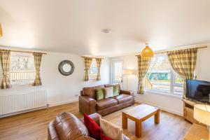 a living room with a couch and a tv at Gorse Lodge 9 with Hot Tub in Belladrum
