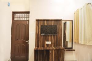 a room with a door and a television and a mirror at Hotel Keshavam inn in Mathura