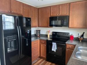 a kitchen with black appliances and wooden cabinets at Stylish, Cozy Corporate Townhome with Pool! in Greensboro