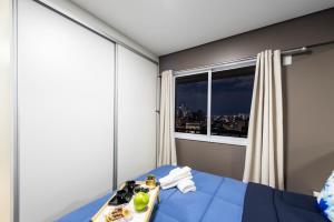 a bedroom with a bed with a tray of food and a window at Rover 1011 Centro in Sao Paulo