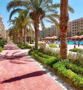 a resort pathway with palm trees and a swimming pool at قريه اكوا فيو الساحل الشمالي in El Alamein