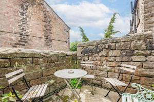 a table and chairs in front of a stone wall at Host & Stay - Nine Ladies in Matlock +3 photos