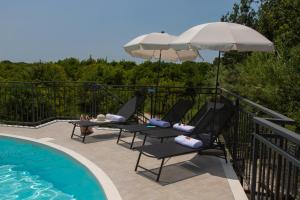 una terrazza con sedie e ombrelloni accanto alla piscina di Villa Tatai Country House by Dimore Trinacria a Belvedere