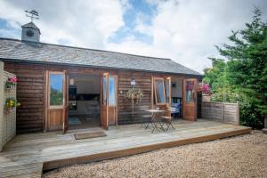 a wooden cabin with a deck with a table at The Tack Room - rural boutique retreat for two in Clapham