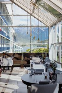 un restaurante con mesas, sillas y ventanas grandes en Brakanes Hotel en Ulvik