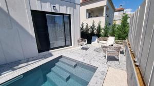 a backyard with a swimming pool and chairs next to a building at Delta House - Beta apartment in Zadar