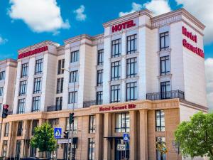 ein großes weißes Gebäude mit einem Hotel darauf in der Unterkunft Garnet Mir Hotel in Taschkent
