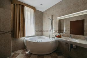 a bathroom with a large tub and a sink at Hotel Rinno in Vilnius