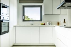 biała kuchnia ze zlewem i oknem w obiekcie NOLA - Nomadic Luxury Villas w mieście Guwes