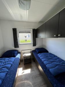 two beds in a small room with a window at Zandput 490 - Camping de Zandput in Vrouwenpolder