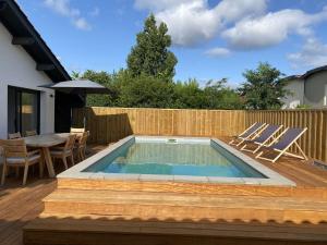 una piscina con sedie e un tavolo su una terrazza di LUTZY Maison moderne au calme piscine a La Teste-de-Buch