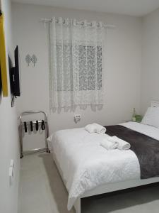 a white bedroom with a bed and a window at וילת הנחלה למשפחות Nahala Villa in Shadmot Devora