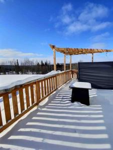 a wooden deck with a bench in the snow at Chez Dorance in Saint-Gabriel