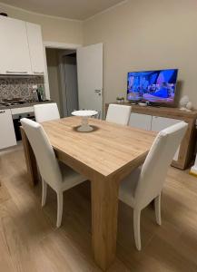 una mesa de madera con sillas blancas en la cocina en B&B CIVICO CINQUE, en Pianella