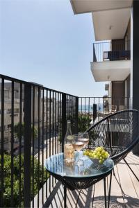 una mesa con copas de vino y uvas en el balcón en Mate ALLENBY - By HOMY, en Tel Aviv