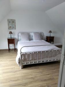 - une chambre dotée d'un grand lit avec des draps et des oreillers blancs dans l'établissement Chez Pascale & Christian, à Langoat