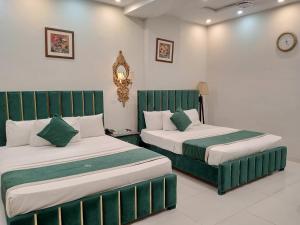 two beds in a room with green and white at Golden One Hotel in Lahore