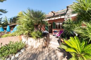 een huis met palmbomen ervoor bij Gavila's Residenza Turistico Alberghiera in Porto Azzurro