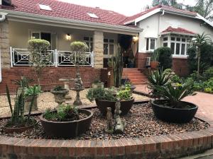 a garden in front of a house with potted plants at St John`s Guest House in Pietermaritzburg
