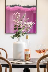 a bottle of wine and a vase of flowers on a table at Mate GEORGE - By HOMY in Tel Aviv