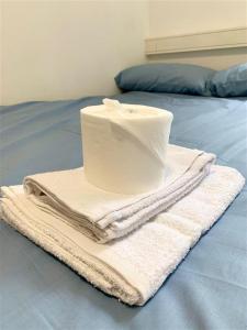 a roll of toilet paper on a pile of towels on a bed at ALTIDO Cosy rooms in Southampton in Southampton
