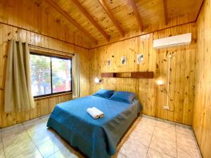 ein Schlafzimmer mit einem Bett in einem Holzzimmer in der Unterkunft Blusky Lodge in Puerto Iguazú