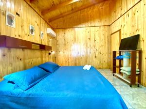 1 dormitorio con 1 cama azul y paredes de madera en Blusky Lodge en Puerto Iguazú