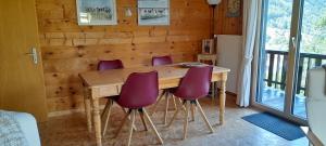 un tavolo in legno con sedie viola in una stanza di Chalet Esher Surrey a Ried-Brig