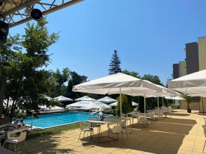 een zwembad met tafels, stoelen en parasols bij St. Sofia Beach Hotel in Kiten
