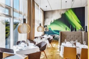 a restaurant with white tables and chairs and a green wall at Akureyri - Berjaya Iceland Hotels in Akureyri