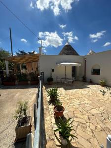 a building with a patio with plants and an umbrella at Trullo Gnoffa in La Correggia