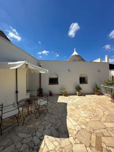 a patio with a table and chairs and an umbrella at Trullo Gnoffa in La Correggia
