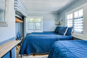 Charming Catalina Gem with Deck Walk to the Beach! في أفالون: سريرين في غرفة مع جدران ونوافذ زرقاء