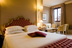 una camera con un grande letto bianco e un divano di Ca' Sagredo Hotel a Venezia