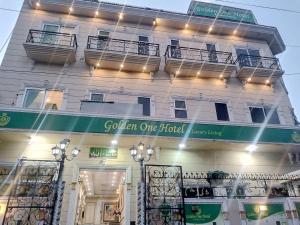 a white building with a green sign on it at Golden One Hotel in Lahore