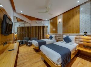 a hotel room with two beds and a flat screen tv at Hotel Surya Executive 3 Star Hotel in Solapur