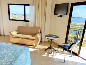 ein Wohnzimmer mit einem Sofa, einem Stuhl und einem TV in der Unterkunft De La Costa Hotel in Encarnación