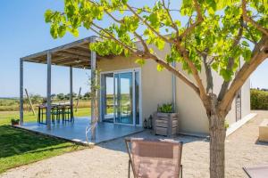 ein Haus mit einer Terrasse mit einem Tisch und einem Baum in der Unterkunft NEW Exclusive Lodges, Marzamemi, Noto in Pachino