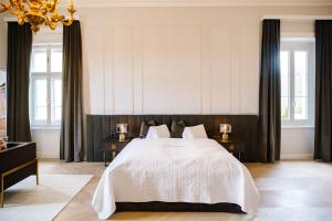 ein Schlafzimmer mit einem großen weißen Bett mit zwei Tischen in der Unterkunft Georgi Schloss - Boutique Hotel in Ehrenhausen