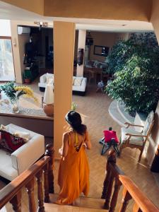 Uma jovem com um vestido laranja a andar pela sala de estar. em The Precious Guesthouse em Sowayma
