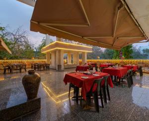 a restaurant with red tables and chairs in the rain at Hotel Surya Executive 3 Star Hotel in Solapur