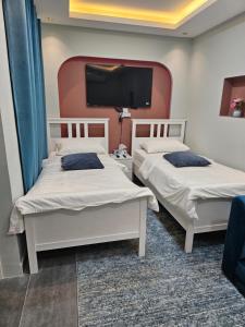 two beds in a room with a tv on the wall at afnan farm in Al Ḩamrānīyah +47 photos