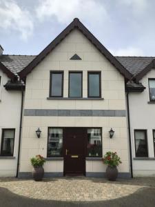 a white building with a black door and windows at Errew Lodge in Mohill