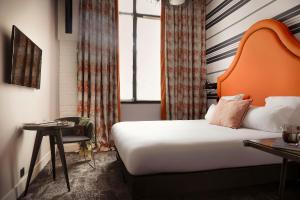 a hotel room with a bed with an orange headboard at H&ocirc;tel Fabric in Paris