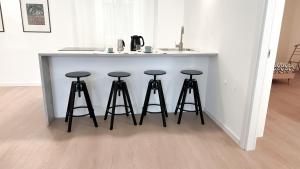una isla de cocina con 4 taburetes bajo un mostrador en Atelier Rimini - Affitti Brevi Italia, en Rímini