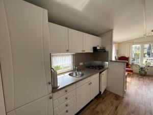 een keuken met witte kasten, een wastafel en een koelkast bij ZP 470 - Camping de Zandput in Vrouwenpolder
