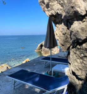 two tables and an umbrella next to the ocean at Apartman Ail 2 in Ulcinj