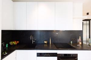 uma cozinha com armários brancos e um balcão preto em Magnificent renovated 4-room apartment - Croisette Carre d'or em Cannes