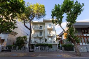 un edificio blanco con árboles delante de él en DimmiDiRimini - Appartamenti in Affitto en Rímini