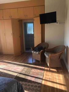 uma sala de estar com 2 cadeiras e uma televisão de ecrã plano em Self-catering two-bedroom flat Scottsville PMB em Pietermaritzburg